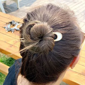 Detail view of U-shaped gold alloy crescent hair fork with shell inlay on a bun