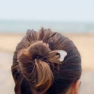 Elegant gold U-shaped metal hair pin with white shell texture worn on a bun hairstyle