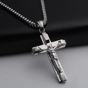 Detail of silver crucifix pendant with 3D Jesus figure on a stainless steel box chain