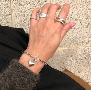 Detail of 925 sterling silver heart bracelet with T-bar clasp and layered infinity rings
