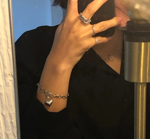 Detailed view of 925 sterling silver heart bracelet and rings worn on the hand