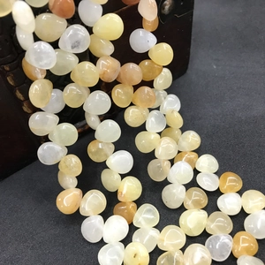 Macro shot of natural teardrop crystals and agate beads pouring from a wooden box