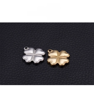 Detailed view of silver and gold clover pendants with heart-shaped petals on black leather
