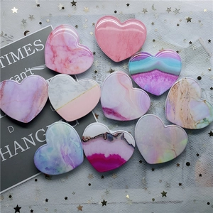 Flat lay of heart-shaped marble pattern phone grips on sparkling mesh backdrop