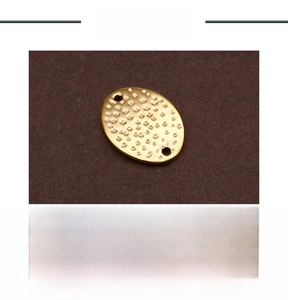 Detailed view of oval hammered stainless steel gold charm with top and bottom holes