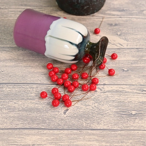 Artistic ceramic vase with purple and white flowing glaze on a wood grain background