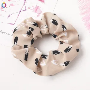 Detail of beige scrunchie with black tulip floral patterns on thick cotton fabric