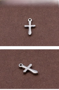 Close-up of a silver cross pendant featuring intricate twisted rope texture and a top loop