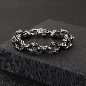 Gothic style stainless steel cross bracelet for men displayed on a black textured box