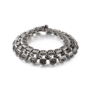 Punk style men's double row stainless steel bracelet with skull head links on white background