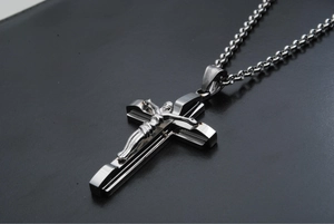 Polished stainless steel crucifix pendant necklace with chain on dark background
