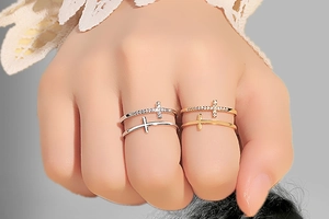 Detail of silver and gold double-layer cross rings with inlaid diamonds on model hand