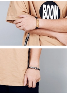 Detail of woven leather bracelet featuring silver and gold skull charms for men