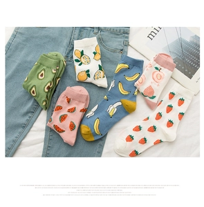 Flat lay of colorful cotton socks with fruit patterns on denim and white sheet
