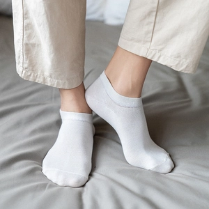 Breathable white low cut cotton socks for men with reinforced toes on a neutral background