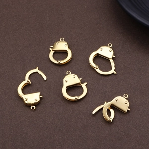 Five golden stainless steel handcuff charms for DIY jewelry making on brown textured background