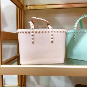 Detailed view of PVC jelly tote bags featuring square stud accents on a metal shelf