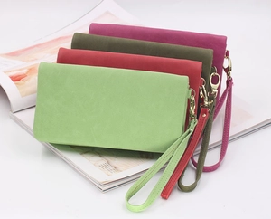 Detail view of colorful suede wristlet wallets in green, red, and purple with gold hardware