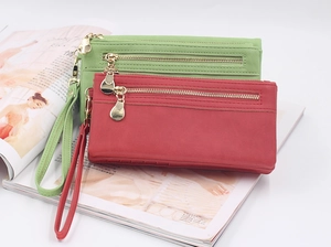 Detail view of long wallets featuring matte texture and double metal zippers with wrist straps