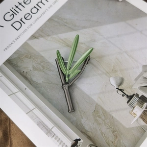 Macro detail of a vintage green bamboo leaf brooch on a marble background with books