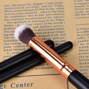Macro shot of dual-tone synthetic bristles and rose gold ferrule on a black makeup brush