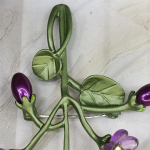 Macro detail of violet flower brooch with green leaves and freshwater pearls