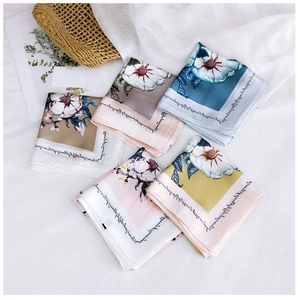 Flat lay of five multi-colored floral silk scarves with elegant decorative props on white cloth