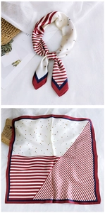 Detail of square silk scarf with red stripes and gold star patterns on white fabric