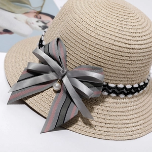 Elegant woven straw sun hat featuring a striped bow and a delicate pearl pendant detail