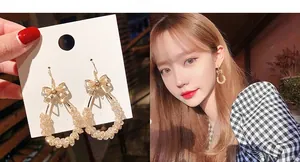 Detail of gold bow earrings with crystal drop pendant shown on model and card