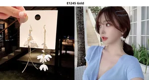 Detailed view of gold asymmetric floral earrings with white petals and beads on model