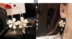 Detail view of gold flower earrings with white petals and crystal accents for women