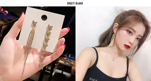 Detailed view of E821 golden asymmetric heart earrings with long crystal tassel fringe