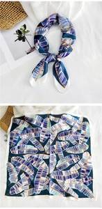 Detail of square silk scarf with blue tropical leaf patterns and orange accents