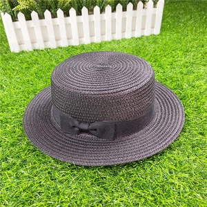 Detail view of the fine straw weave and black ribbon bow on a classic boater hat