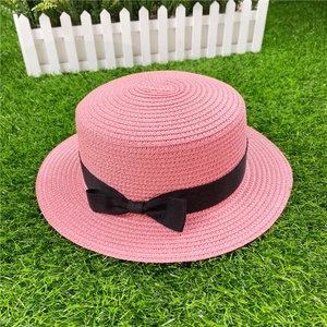 Close-up of pink woven straw sun hat featuring a delicate black ribbon bow detail