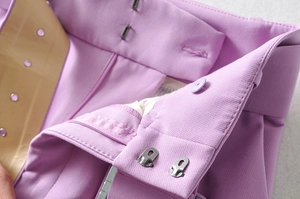 Primer plano de pantalón lavanda de talle alto con ganchos metálicos y botón de resina