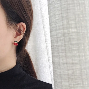 Close-up of red cherry earrings with green leaves on model with minimalist background