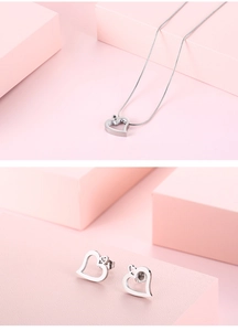 Elegantes silbernes Herz-Schmuckset mit hohlgeformter Halskette und Ohrringen auf rosa Ständern