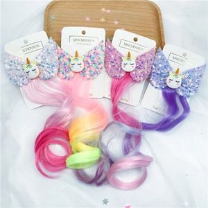 Detail of glittery unicorn hair clips with vibrant rainbow curly hair extensions on cards