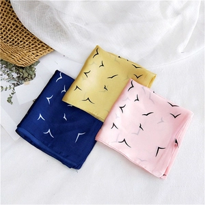 Silk square scarf featuring minimalist bird patterns in navy, yellow and pink on white linen