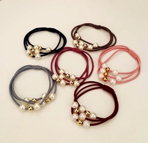 Close-up of three-strand elastic hair ties with white faux pearls and gold beads
