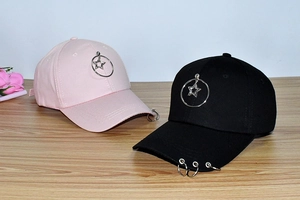 Detail of pink and black baseball caps with silver star rings on a wooden desk