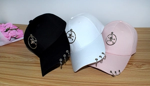 Three trendy baseball caps in black, white, and pink with metal ring and skull accents