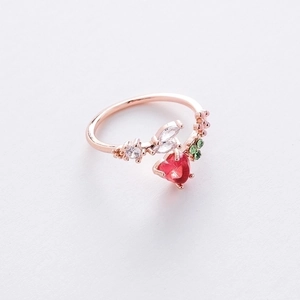 Detail of rose gold strawberry ring with red heart stone and green leaf accents