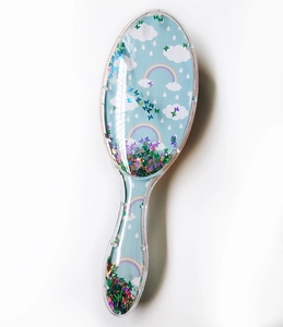 Macro detail of transparent air cushion hairbrush with blue liquid, glitter, and rainbow