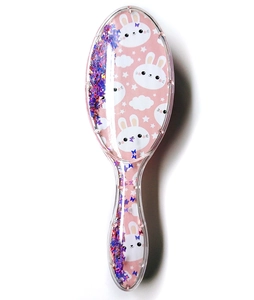 Macro shot of pink glitter hairbrush featuring cute white rabbit and star patterns