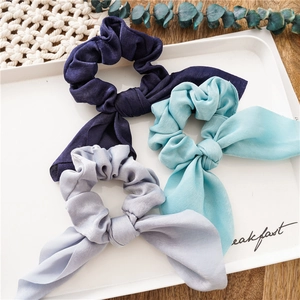 Close-up of silk-textured hair scrunchies with long ribbons in blue and silver tones