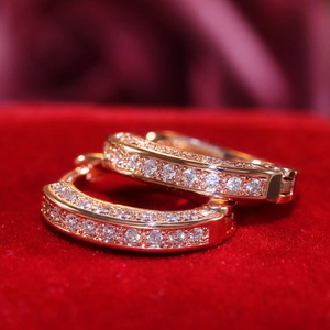 Close-up of gold U-shaped hoop earrings with micro-paved white zircon on red velvet