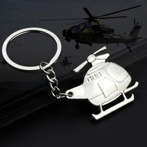 Macro shot of a silver metal helicopter keychain on a dark reflective surface